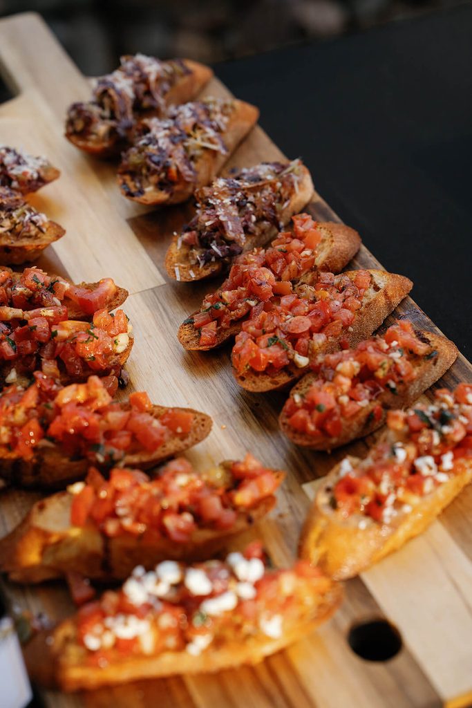 Tray of bruschetta appetizers served during an outdoor wedding reception.
